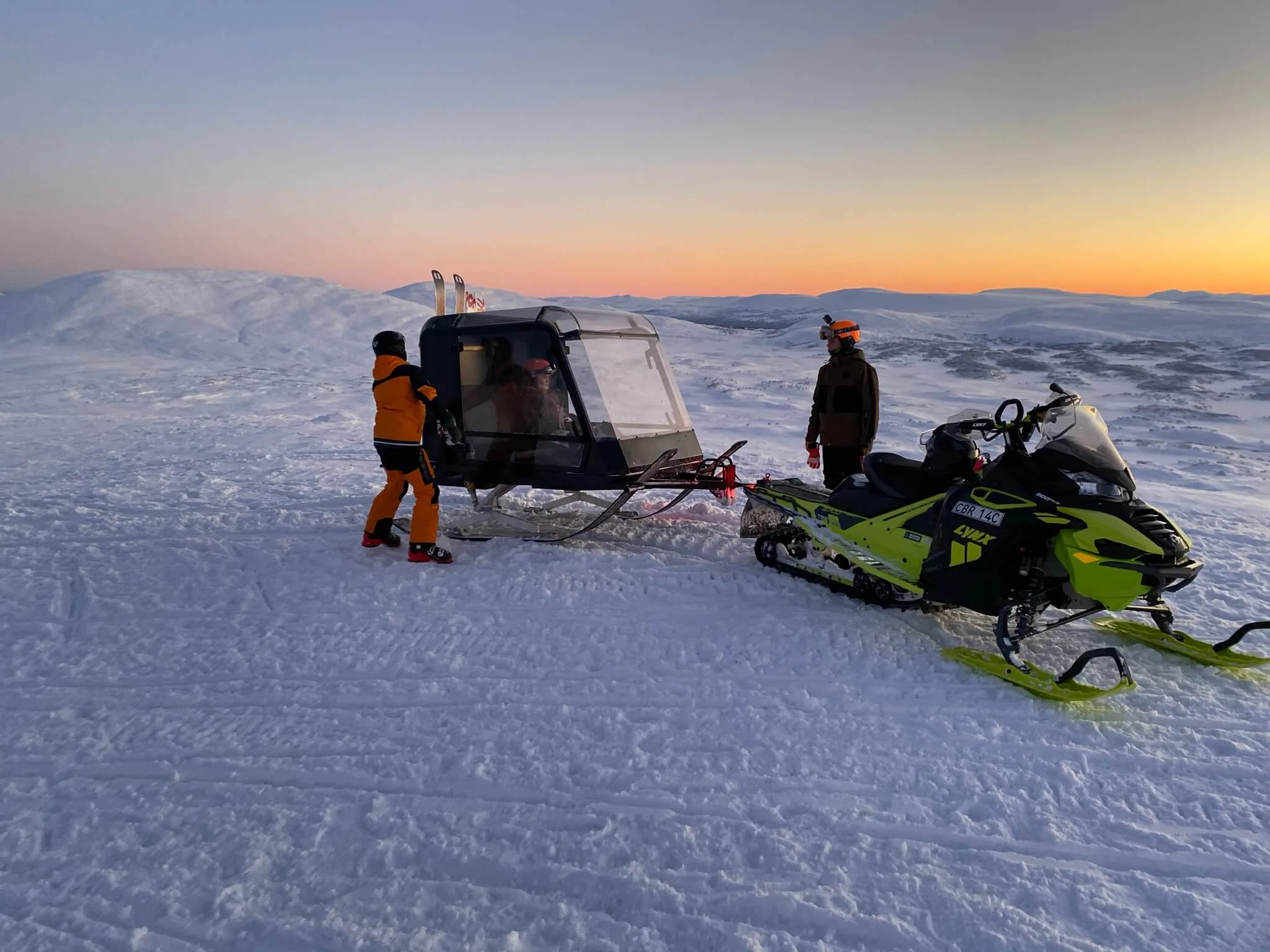 Familie ved Pulkapanorama og snøscooteren på snaufjellet i skumringen