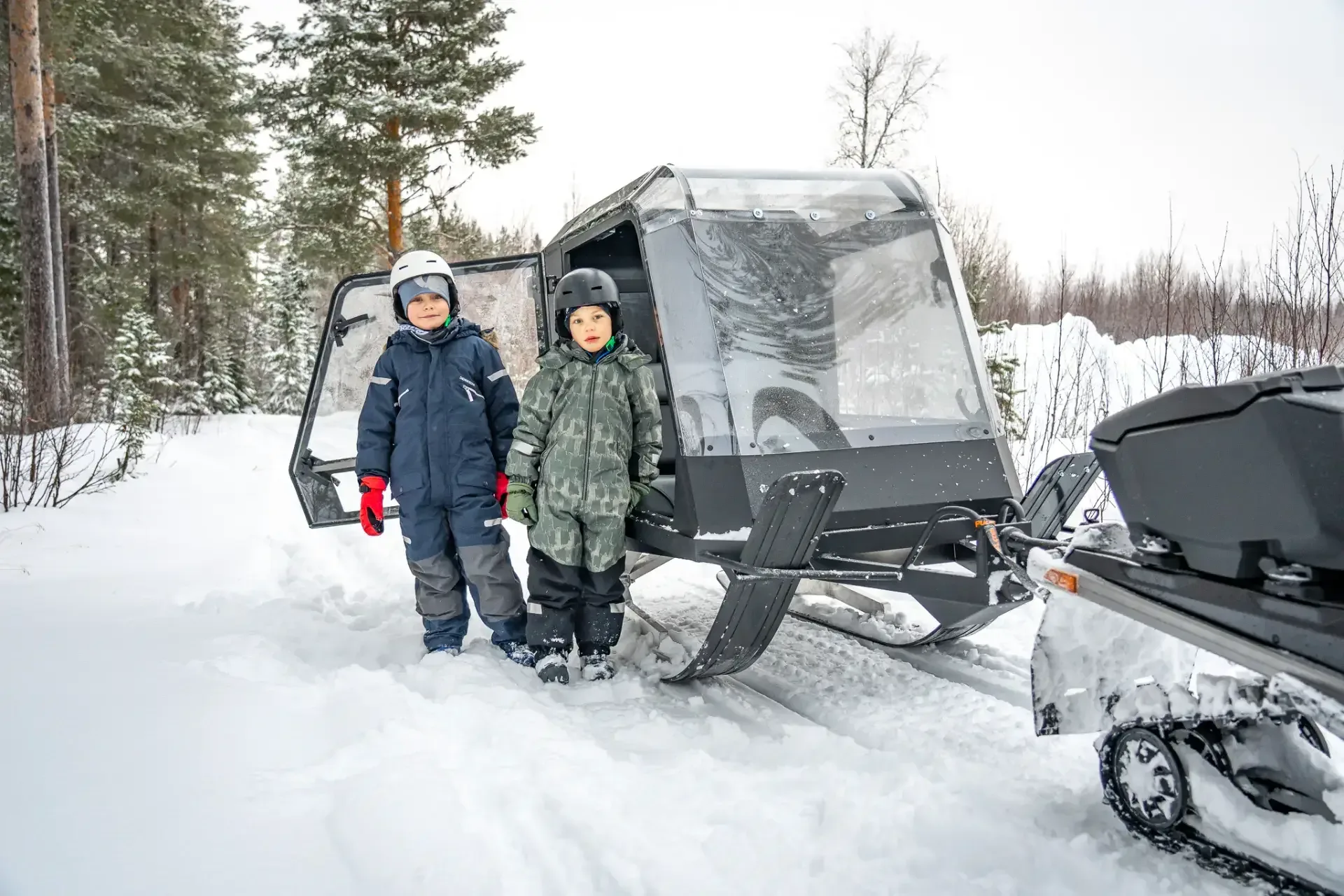 Kaksi lasta Pulkapanoraman edessä metsässä