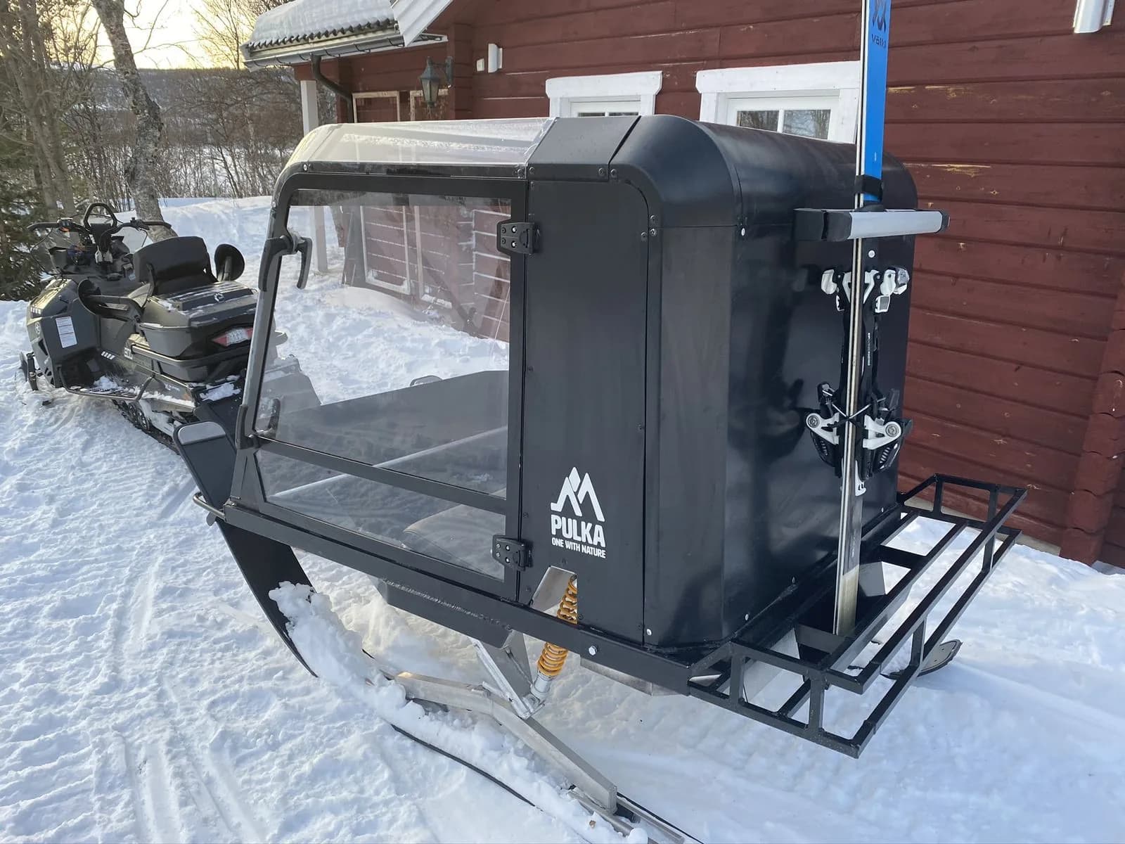 Pulkapanorama parkerad vid en stuga med skidor fastspända i skidhållaren